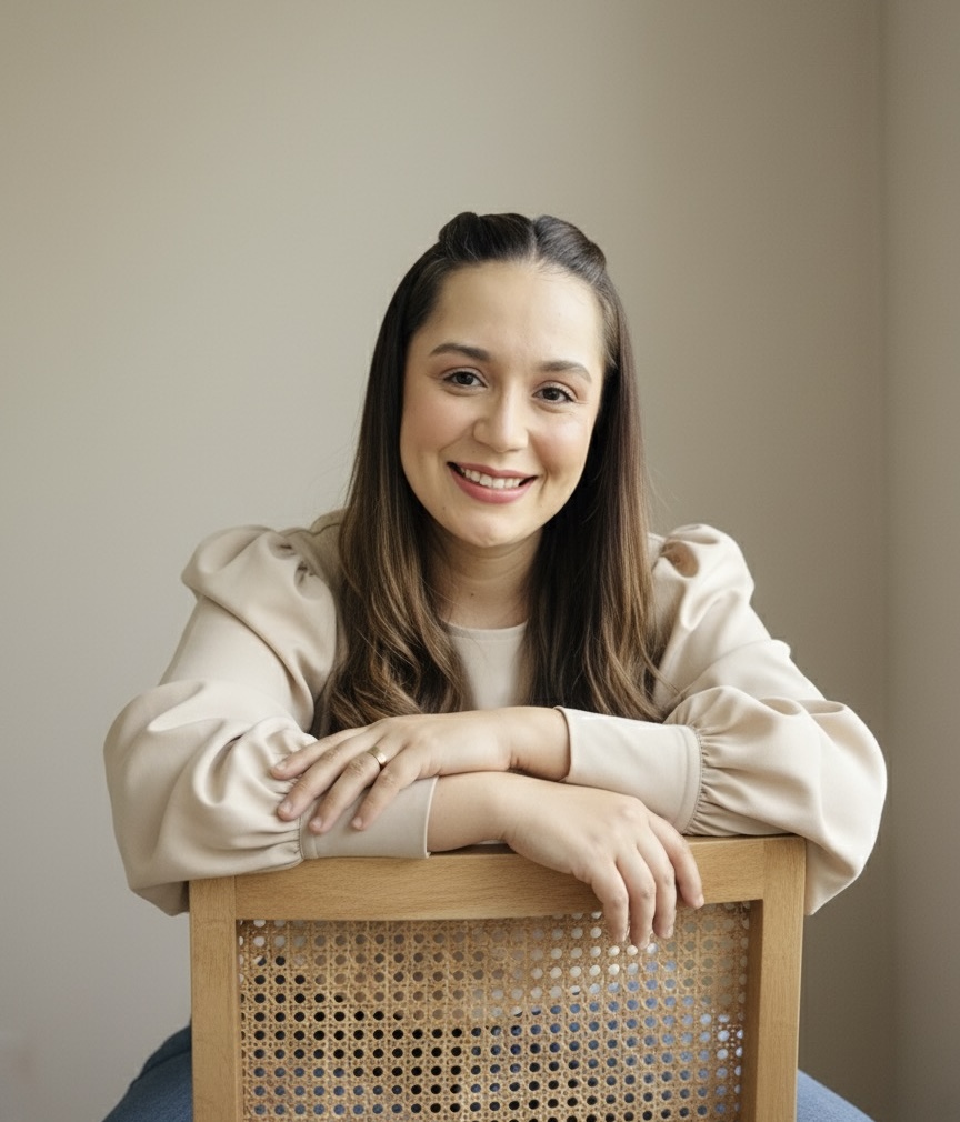 Carliane Parente de blusa bege, sentada em uma cadeira de palhinha.